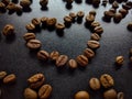 Coffee beans on a black background. Heart shape made of coffee beans. Coffee texture and background.